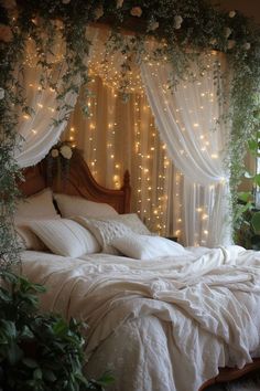 a bed with white linens and lights on the headboard is surrounded by greenery