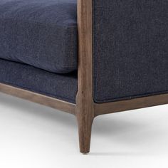 a close up view of the back of a couch with dark blue fabric and wooden legs