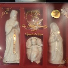 three white figurines in a red box with gold trimmings on them