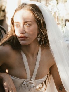 a woman in a wedding dress sitting on the ground with her face covered by a veil