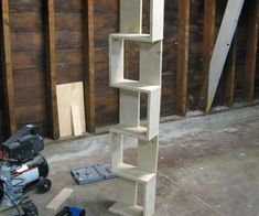 a tall white shelf sitting on top of a floor next to a pile of tools