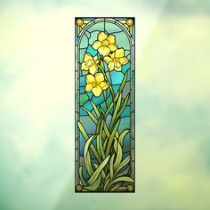 a stained glass window with yellow flowers in the center and green grass below, against a blue sky background