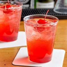 two glasses filled with red liquid sitting on top of a table