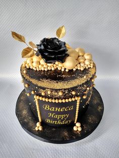 a black and gold birthday cake with a rose on top