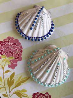 two seashells decorated with blue and white beads on a striped tablecloth background