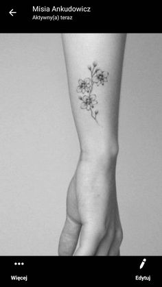 a woman's arm with a small flower tattoo on the left side of her hand