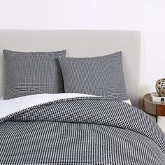 a bed with black and white checkered bedspread, pillows and night stands