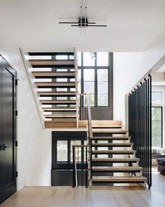 the stairs in this modern house are made of wood and black metal, with glass doors on both sides