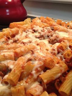 a close up of a plate of pasta with meat and cheese on it, sitting on a stove top