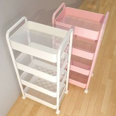 two white and pink baby cribs sitting on top of a hard wood floor