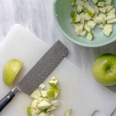 an apple is cut up on a cutting board next to a knife and some apples