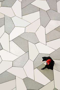 an overhead view of a person walking on the ground with an umbrella over their head