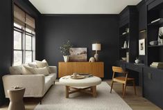 a living room with black walls and white carpeted flooring, furniture and decor