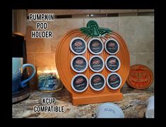 an orange pumpkin shaped pod holder with eight cups in front of it on a kitchen counter