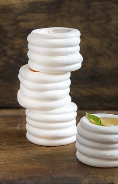 a stack of white vases sitting on top of a wooden table next to each other