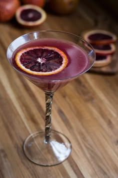 a blood orange martini is garnished with an orange slice