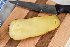 a piece of cheese on a cutting board next to a knife