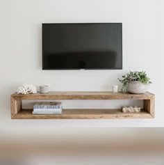 a flat screen tv mounted above a wooden shelf