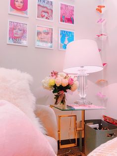 a pink bedroom with pictures on the wall and a table with flowers in front of it