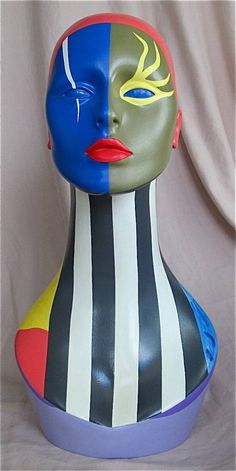 a colorfully painted female mannequin head sitting in front of a white background