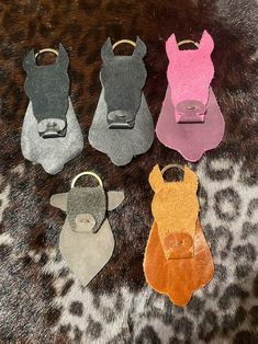 four different colored leather dog tags sitting on top of a leopard print rug