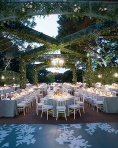 an outdoor dining area with tables and chairs set up for formal dinner under the pergolated canopy