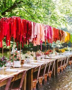 a long table with lots of clothes hanging from it's poles and flowers in vases