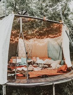 an outdoor tent is set up in the woods with lights strung from it's sides