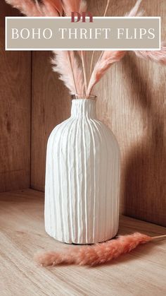 a white vase with pink feathers in it and the words boho thrift flips