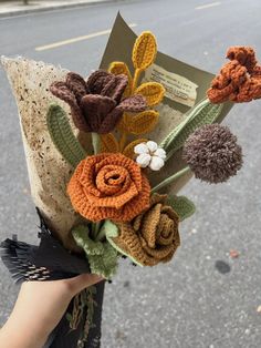 a person holding a bouquet of flowers in their hand on the side of the road