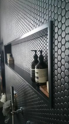 two bottles are sitting on a shelf in the corner of a room with metal mesh covering