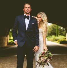 a man and woman in formal wear standing next to each other on a cobblestone walkway