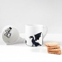 a coffee cup and some crackers on a white table with a black dragon mug