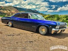 an old blue car parked in the dirt