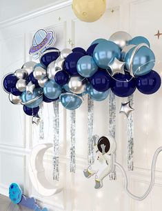 a bunch of blue and silver balloons hanging from the side of a white door with an astronaut on it