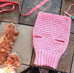 a pink knitted bag sitting on top of a floor next to a stuffed animal