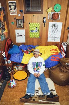 a man sitting on top of a bed in a room filled with pictures and other items