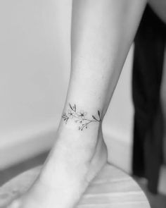 a woman's foot with a small flower tattoo on her left ankle and the bottom part of her leg