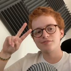 a young man with glasses making the peace sign