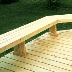 a wooden bench sitting on top of a wooden floor next to green grass and trees