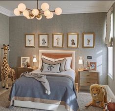 a bedroom decorated in gray and white with giraffes hanging on the wall