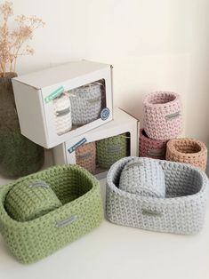 four knitted baskets sitting on top of a white counter next to a microwave oven