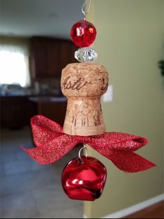 a wine cork ornament with two red hearts hanging from it's side