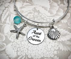 "This elegant bangle will make a beautiful and sentimental gift that will best express your gratitude and love for a wonderful Aunt. ✿ This bangle includes: ♥ starfish charm (20 mm) ♥ shell charm (17 mm) ♥ 8mm glass bead (aquamarine color) ♥ circle charm (20 mm) that reads: \"Aunt of the Groom\" ♥ adjustable bangle 60mm in size (expandable to fit wrist 7-8\") ✿ The bangle is made from 1.5mm (14 gauge) wire - the standard gauge for the bangle. ✿ optional necklace (18-inch) OR keychain ✿ Leave a c Customizable Adjustable Bangle For Wedding, Customizable Adjustable Wedding Bangle, Customizable Wedding Bracelets, Silver Wedding Charm Bracelet, Customizable Silver Charm Bracelet For Wedding, Starfish Jewelry, Aquamarine Color, Charming Quotes, Standard Gauge