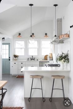 a kitchen with two stools next to an island