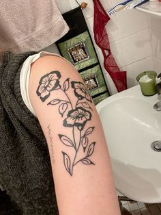 a woman with a tattoo on her arm is sitting in front of a bathroom sink