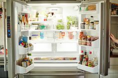 an open refrigerator with the door wide open and full of food in it's left side