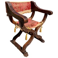 an old wooden chair with tassels and red fabric on it's back