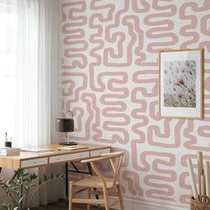 a desk and chair in front of a pink wallpapered room with a window