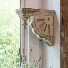 an old clock on the side of a window sill next to flowers and plants